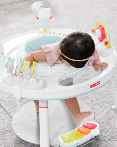 Baby playing in an activity center with toys and piano keys.