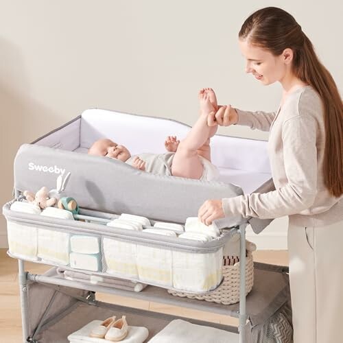 Mother changing baby's diaper on changing table with storage.