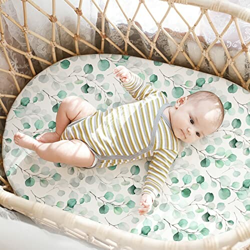 Baby lying in a crib with a leaf-patterned sheet.