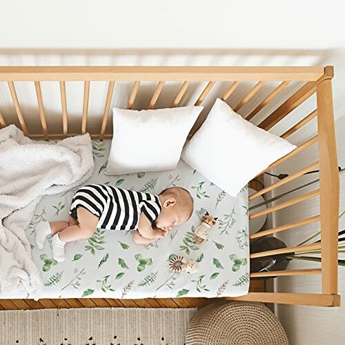 Baby sleeping in a wooden crib with pillows and blanket.