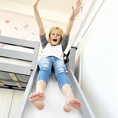 Child joyfully sliding down a slide from a bunk bed.