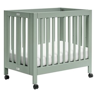 Green baby crib with wheels and white mattress