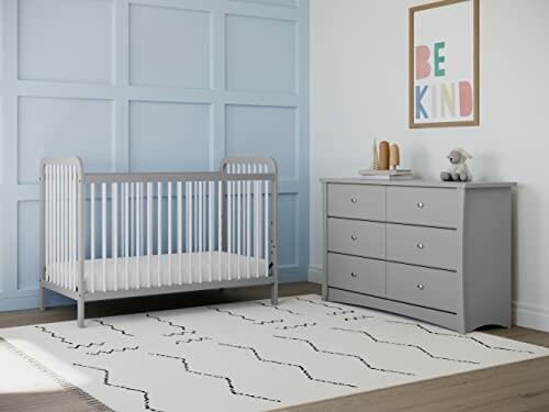 Modern nursery with crib, dresser, and decor.