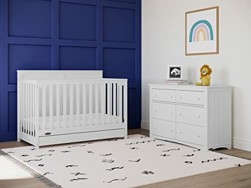 Modern nursery room with white crib and dresser, blue accent wall, and rainbow artwork.