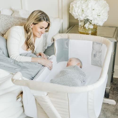 Mother watching baby sleeping in a bassinet