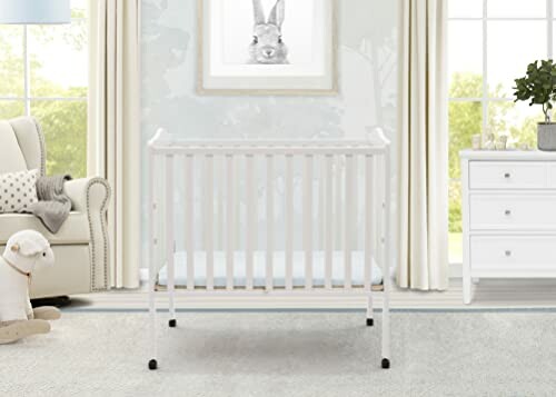 White baby crib in a nursery with a rabbit picture on the wall.