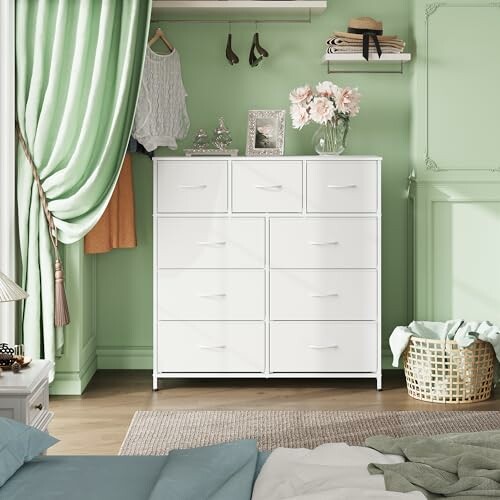 White dresser in green-themed bedroom with decor and basket.