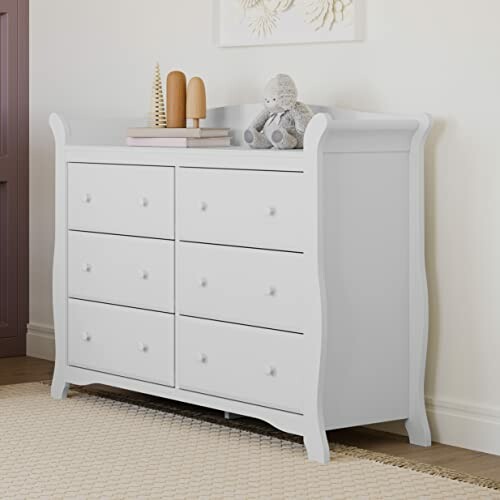 White dresser with stuffed toy and wooden decor on top.